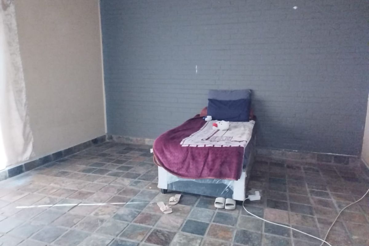 A bedroom featuring slate tile flooring and a dark grey painted brick feature wall.