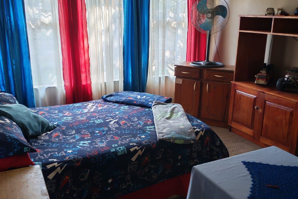 A bedroom featuring built-in cabinetry and security bars on the windows, requiring cosmetic updates to improve the overall aesthetic and condition.
