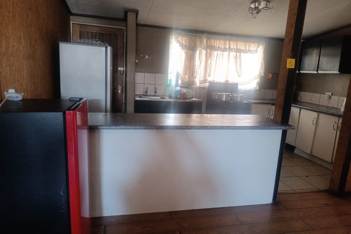 A dated kitchen featuring a breakfast bar, laminate countertops, and tiled backsplash, offering potential for a modern renovation.