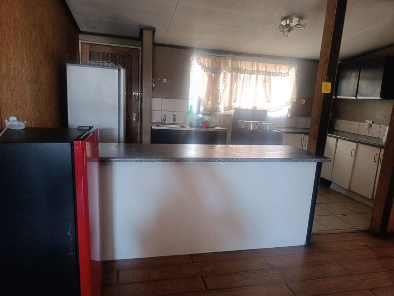A dated kitchen featuring a breakfast bar, laminate countertops, and tiled backsplash, offering potential for a modern renovation.