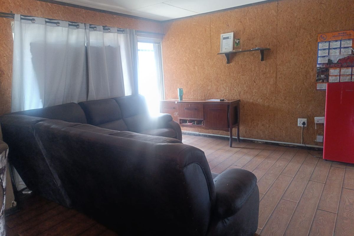 Living room featuring wood-look tiled flooring and OSB wall paneling, offering a rustic aesthetic that could be enhanced with modern finishes.