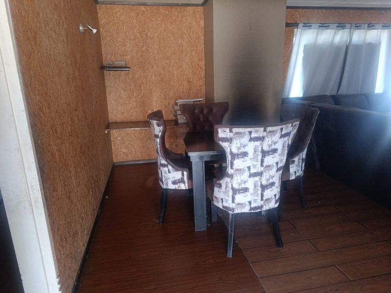 Dining area featuring wood-look laminate flooring and oriented strand board wall paneling with built-in shelving.