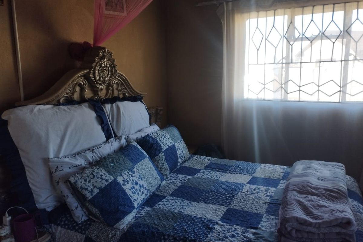 A bedroom featuring a window with installed security burglar bars, providing natural light and essential security features.