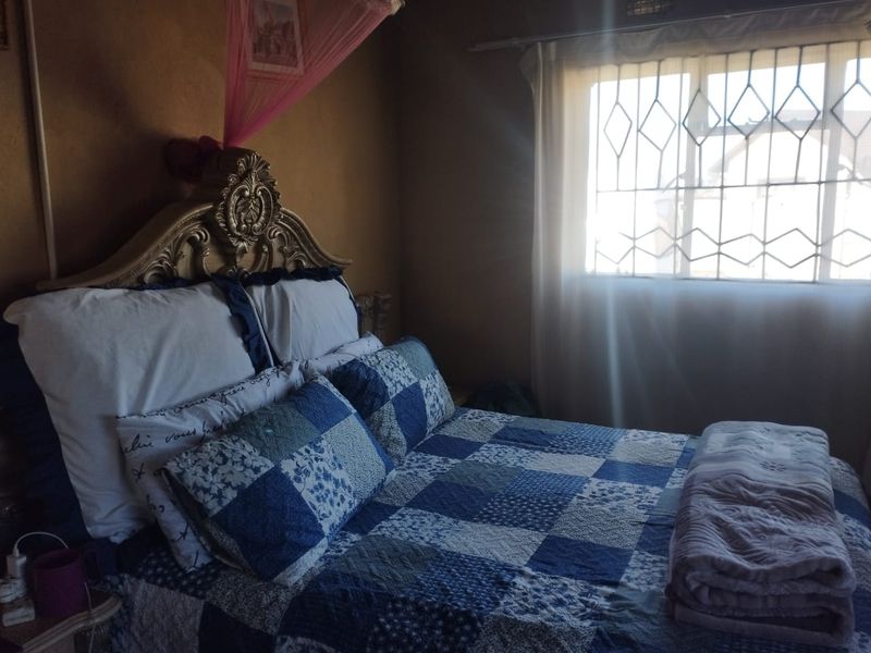 A bedroom featuring a window with installed security burglar bars, providing natural light and essential security features.