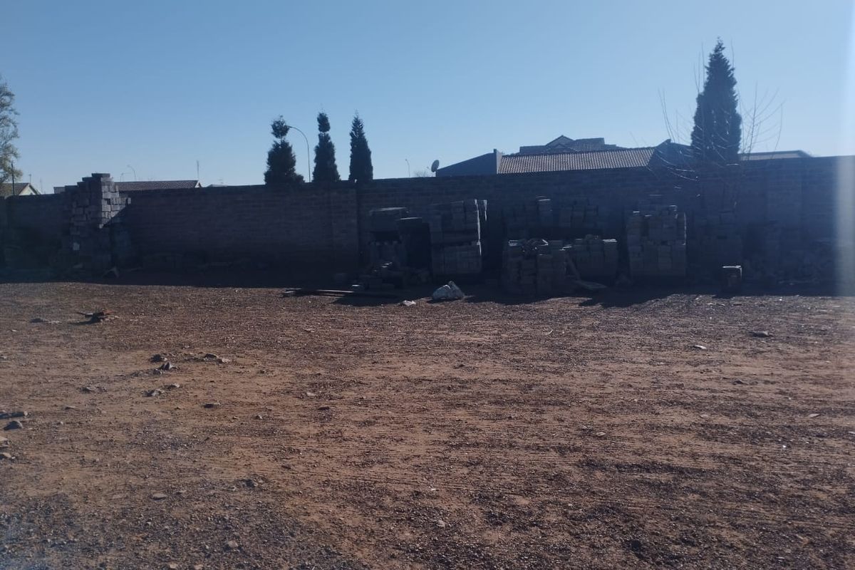 A large, undeveloped rear yard area featuring a perimeter masonry wall and unlandscaped ground, offering significant potential for landscaping or outdoor development.