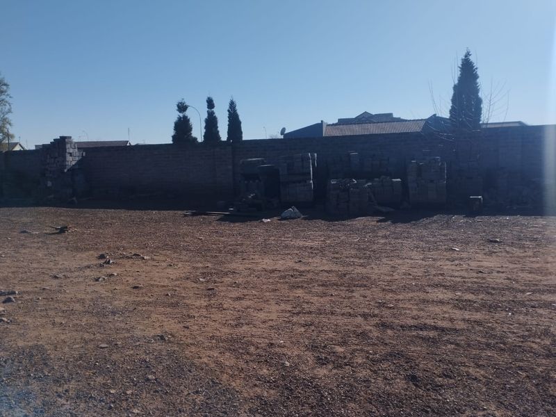 A large, undeveloped rear yard area featuring a perimeter masonry wall and unlandscaped ground, offering significant potential for landscaping or outdoor development.