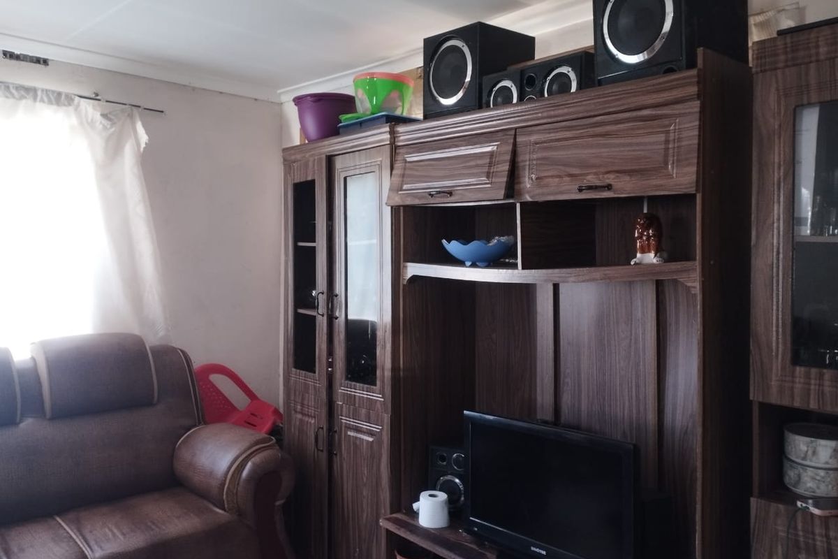 A living room area featuring a large built-in wooden wall unit and natural light from a side window.