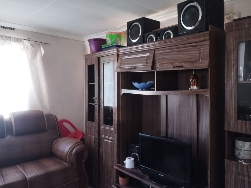 A living room area featuring a large built-in wooden wall unit and natural light from a side window.
