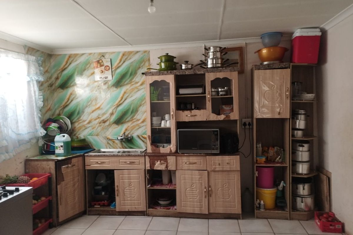 A functional kitchen area featuring built-in cabinetry, a sink, and tiled splashbacks, offering potential for modernization and aesthetic updates.
