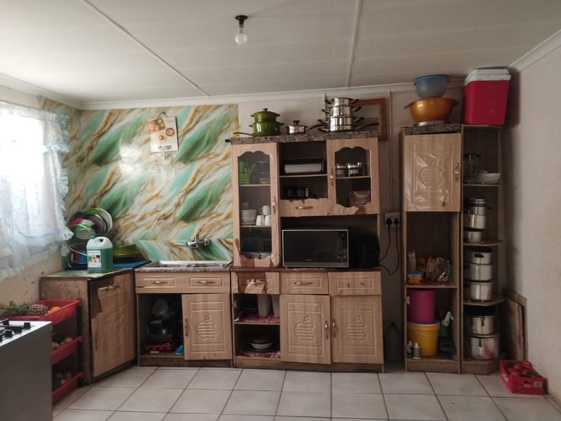 A functional kitchen area featuring built-in cabinetry, a sink, and tiled splashbacks, offering potential for modernization and aesthetic updates.