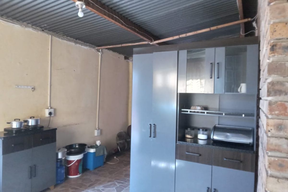 A functional kitchen area featuring modern grey cabinetry, exposed brickwork, and a corrugated metal ceiling, offering potential for further renovation and aesthetic improvement.
