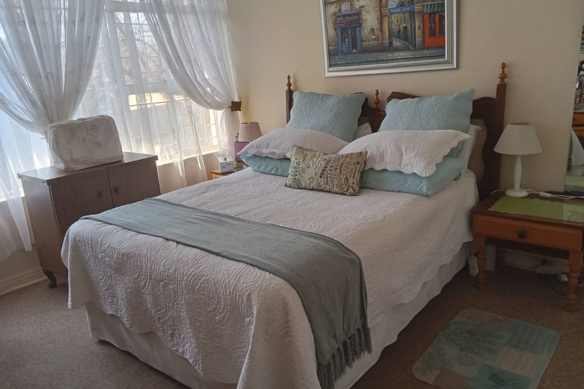 A cozy bedroom featuring carpeted flooring and a large window that allows for natural light.