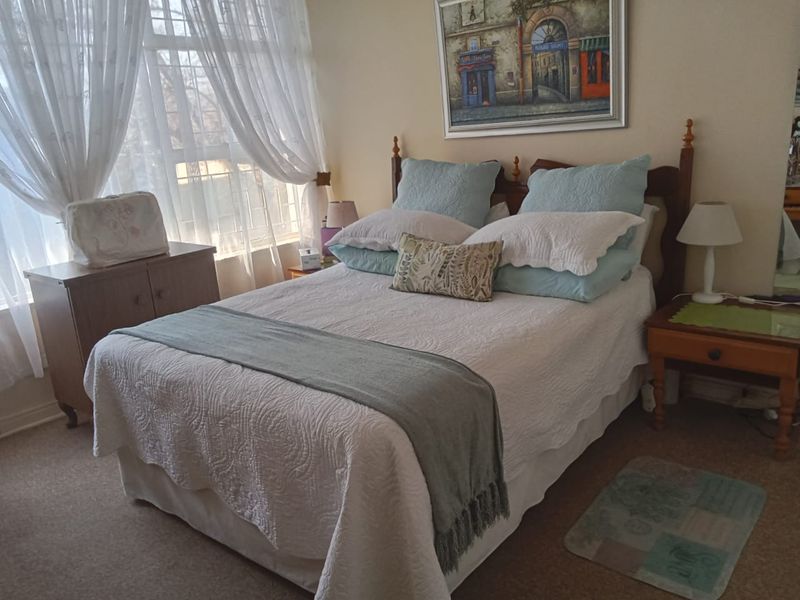 A cozy bedroom featuring carpeted flooring and a large window that allows for natural light.