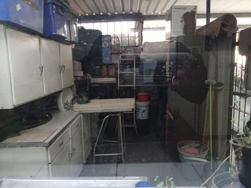 A utility or storage space featuring built-in cabinetry and a sink, currently used for general storage.