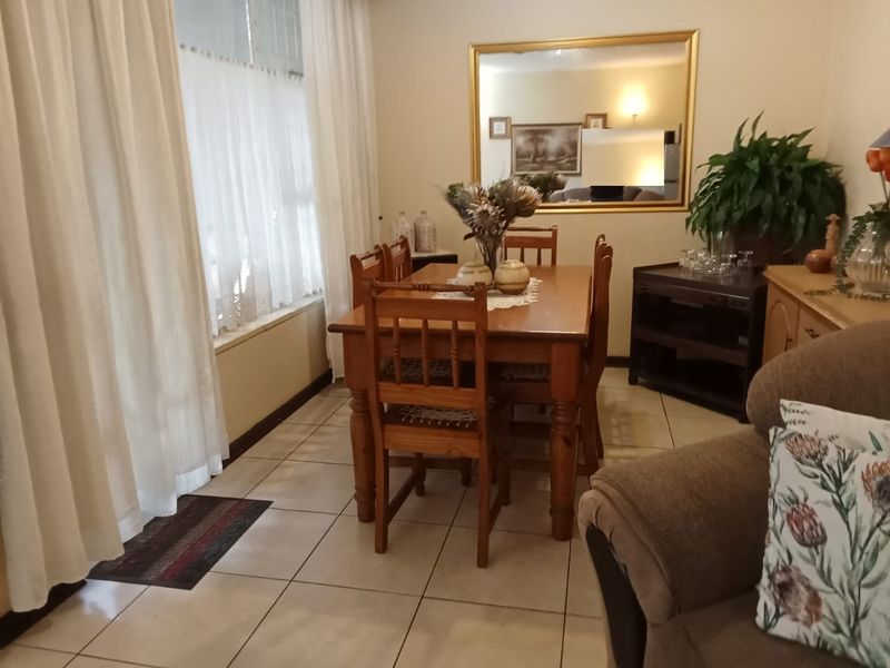 A functional dining room featuring tiled flooring and a large window, providing a bright and practical space for family meals.