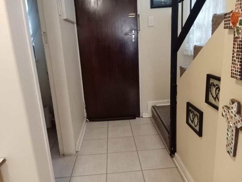 Entryway featuring tiled flooring and a staircase with a metal handrail, leading to an internal door and adjacent utility space.