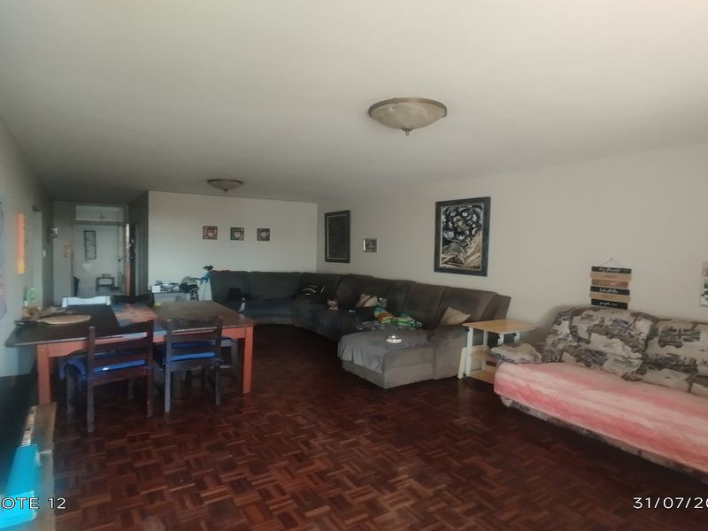 Spacious open-plan living and dining area featuring traditional parquet flooring and neutral wall finishes.