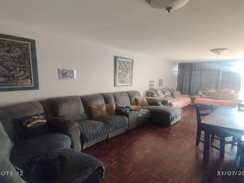Spacious open-plan living and dining area featuring traditional parquet flooring and natural light from the adjacent balcony.