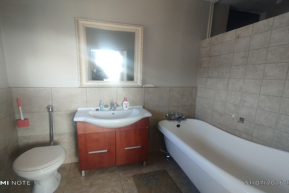 A functional bathroom featuring a vanity cabinet with basin, a freestanding bathtub, and neutral wall tiling.