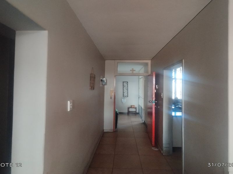 A functional apartment hallway featuring tiled flooring and an intercom system, providing access to adjacent rooms.