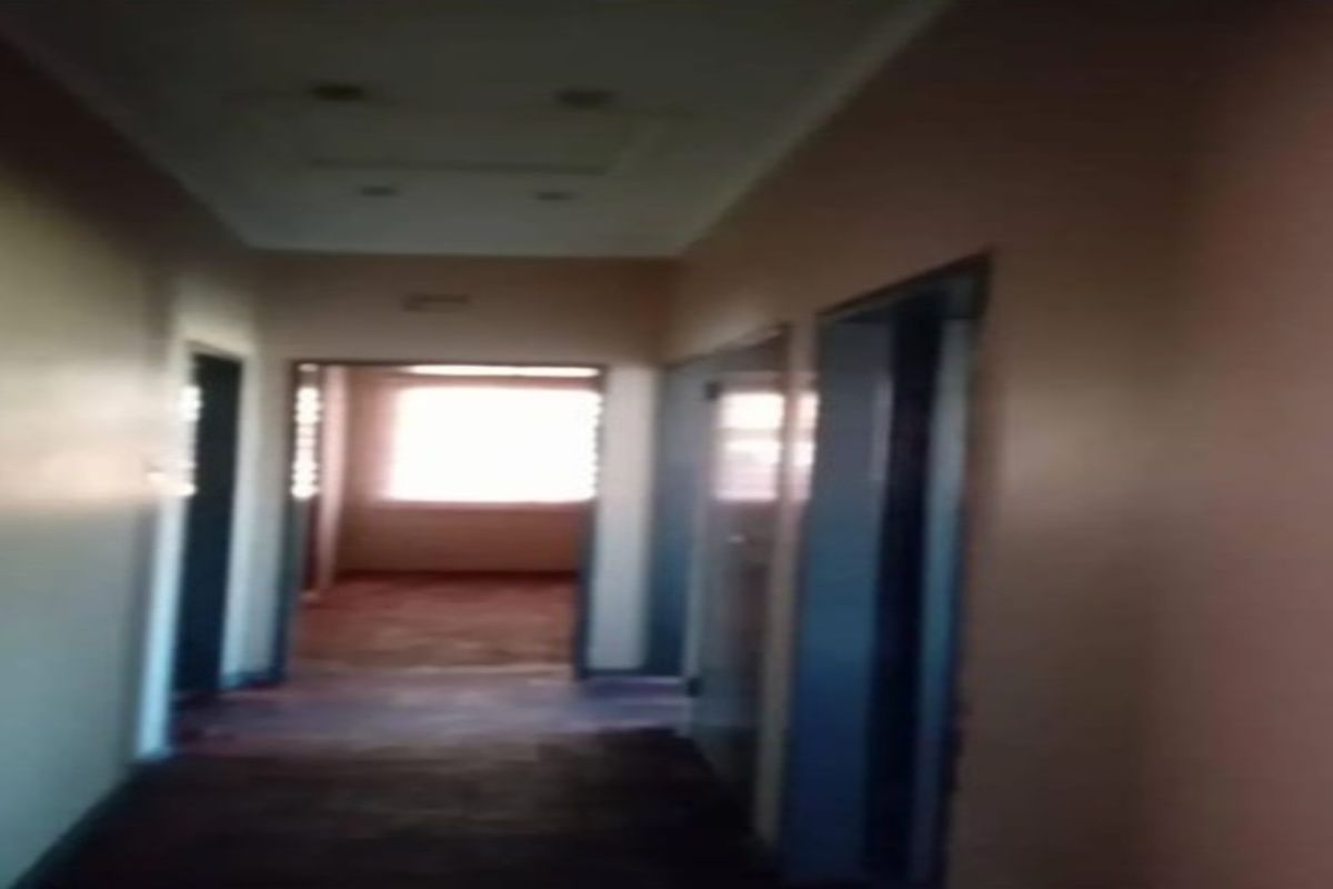 A dimly lit, empty residential hallway with multiple internal doorways leading to adjacent rooms.