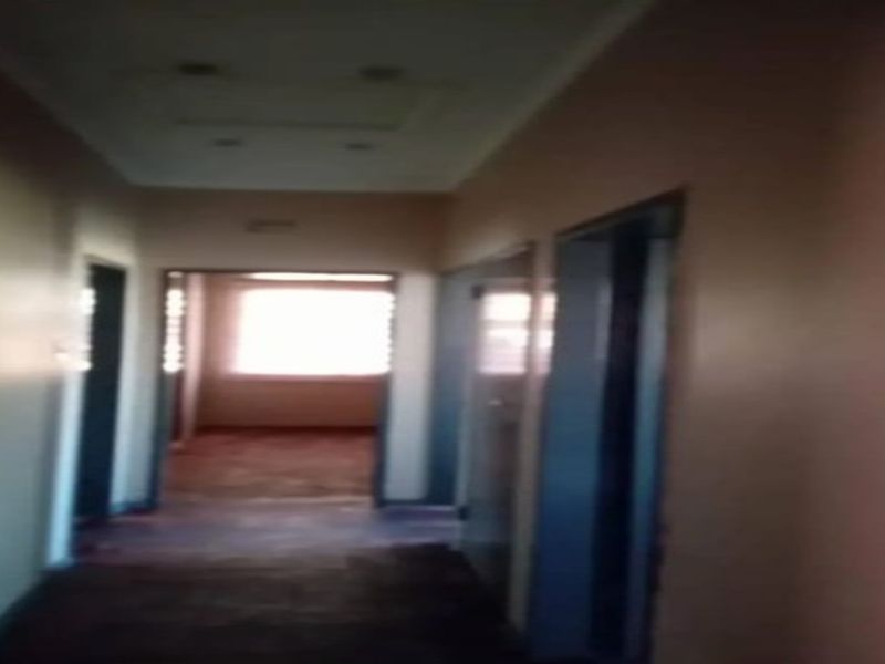 A dimly lit, empty residential hallway with multiple internal doorways leading to adjacent rooms.