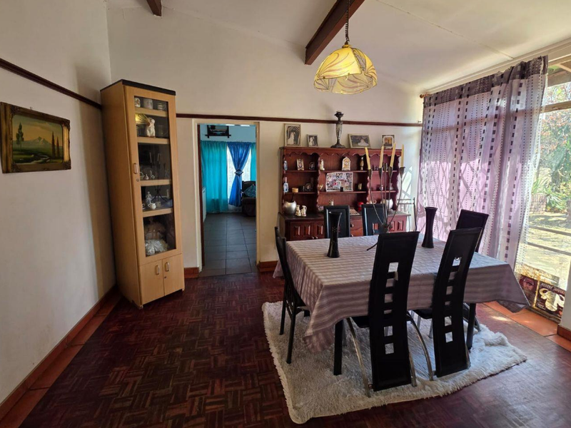 Dining room featuring classic parquet flooring, exposed timber ceiling beams, and a sliding glass door providing natural light and garden access.