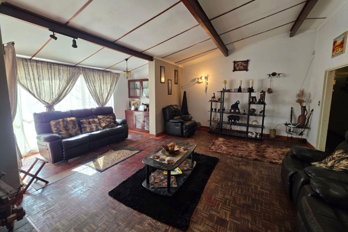 Spacious living room featuring exposed timber ceiling beams, traditional parquet flooring, and built-in cabinetry, offering a classic layout with potential for modernization.