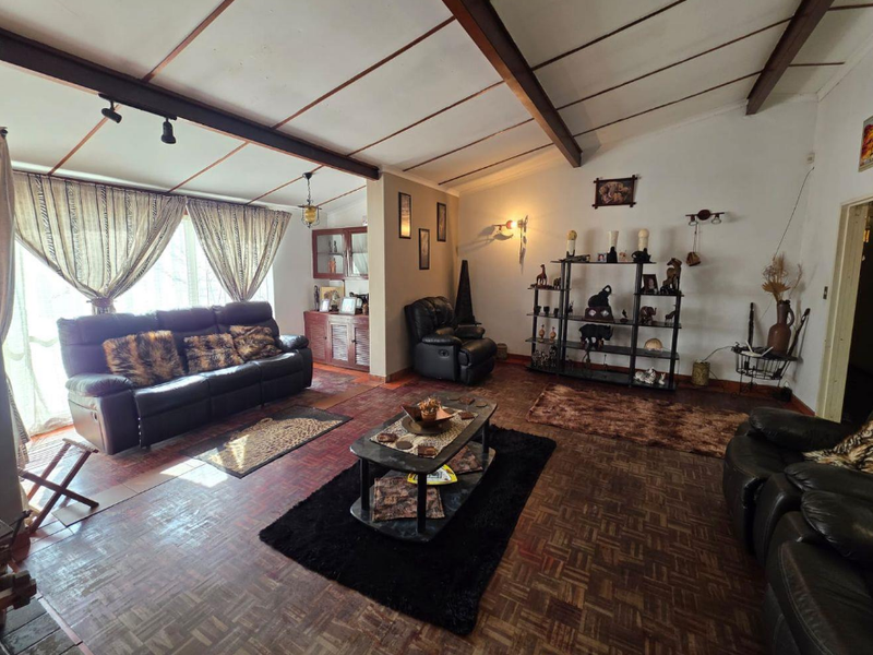 Spacious living room featuring exposed timber ceiling beams, traditional parquet flooring, and built-in cabinetry, offering a classic layout with potential for modernization.