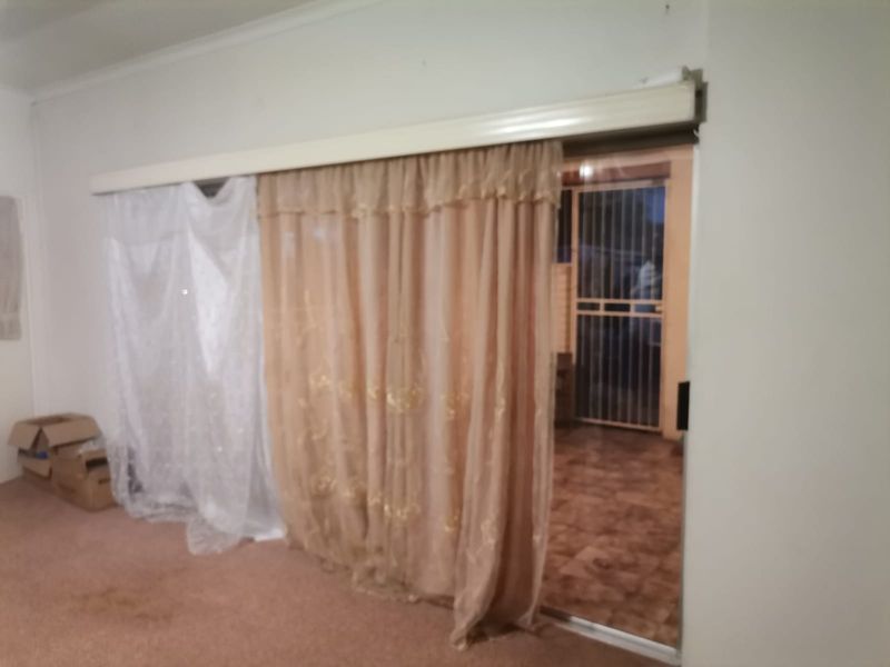 A living room area featuring a large sliding glass door with curtain rails, leading out to an exterior space.