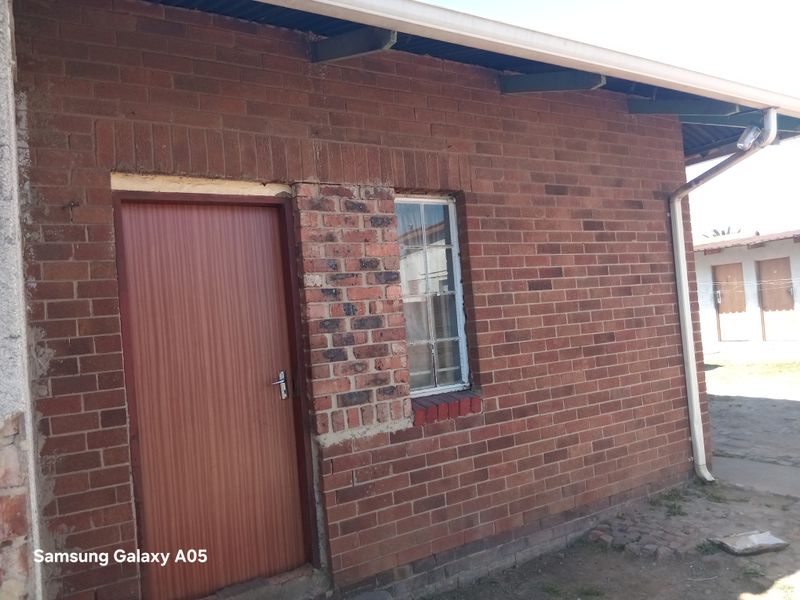 Exterior view of a face brick building featuring a single door, window, and exposed roof rafters.