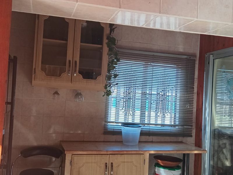 A functional scullery or prep area featuring built-in wooden cabinetry, tiled wall finishes, and a sliding door providing access to adjacent living spaces.