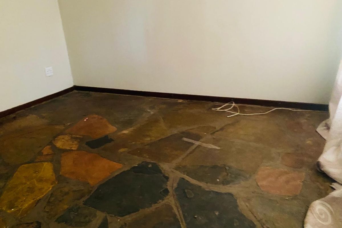 An empty bedroom featuring rustic flagstone flooring and simple wall finishes, offering a blank canvas for potential renovation or interior design updates.