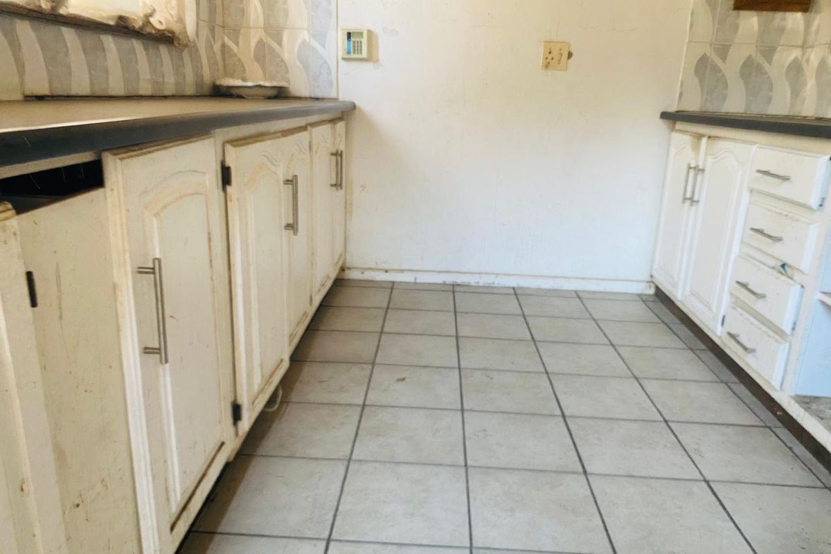 A dated kitchen space featuring original cabinetry, laminate countertops, and tiled flooring, offering a blank canvas for a complete modern renovation.