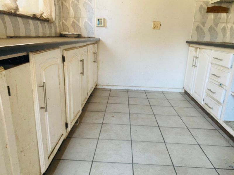 A dated kitchen space featuring original cabinetry, laminate countertops, and tiled flooring, offering a blank canvas for a complete modern renovation.
