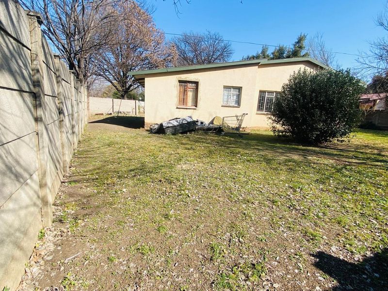 Rear view of the property showing a large garden area, precast concrete boundary wall, and the rear building facade.