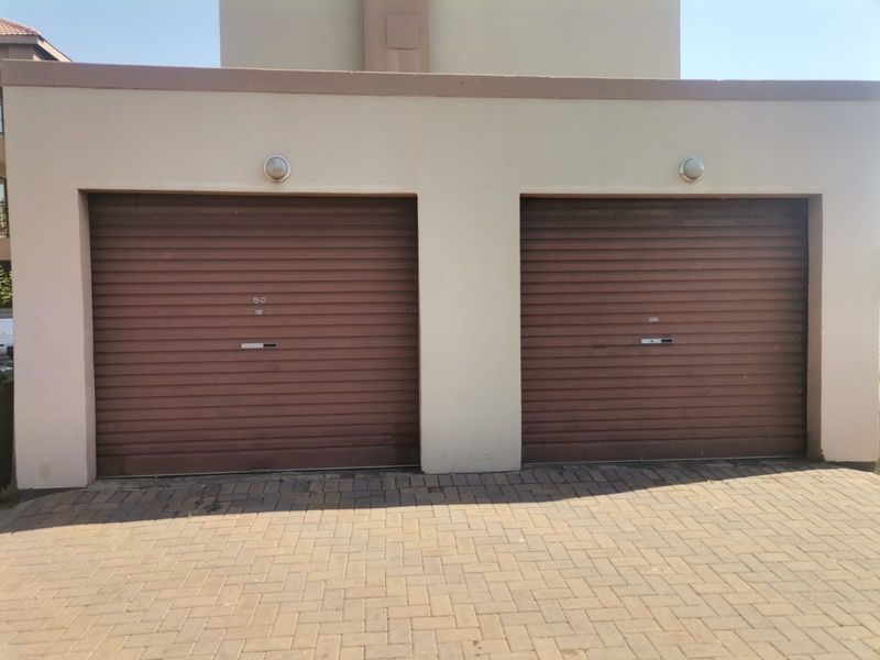 A double garage featuring brown roller doors and a paved driveway, providing secure parking for two vehicles.