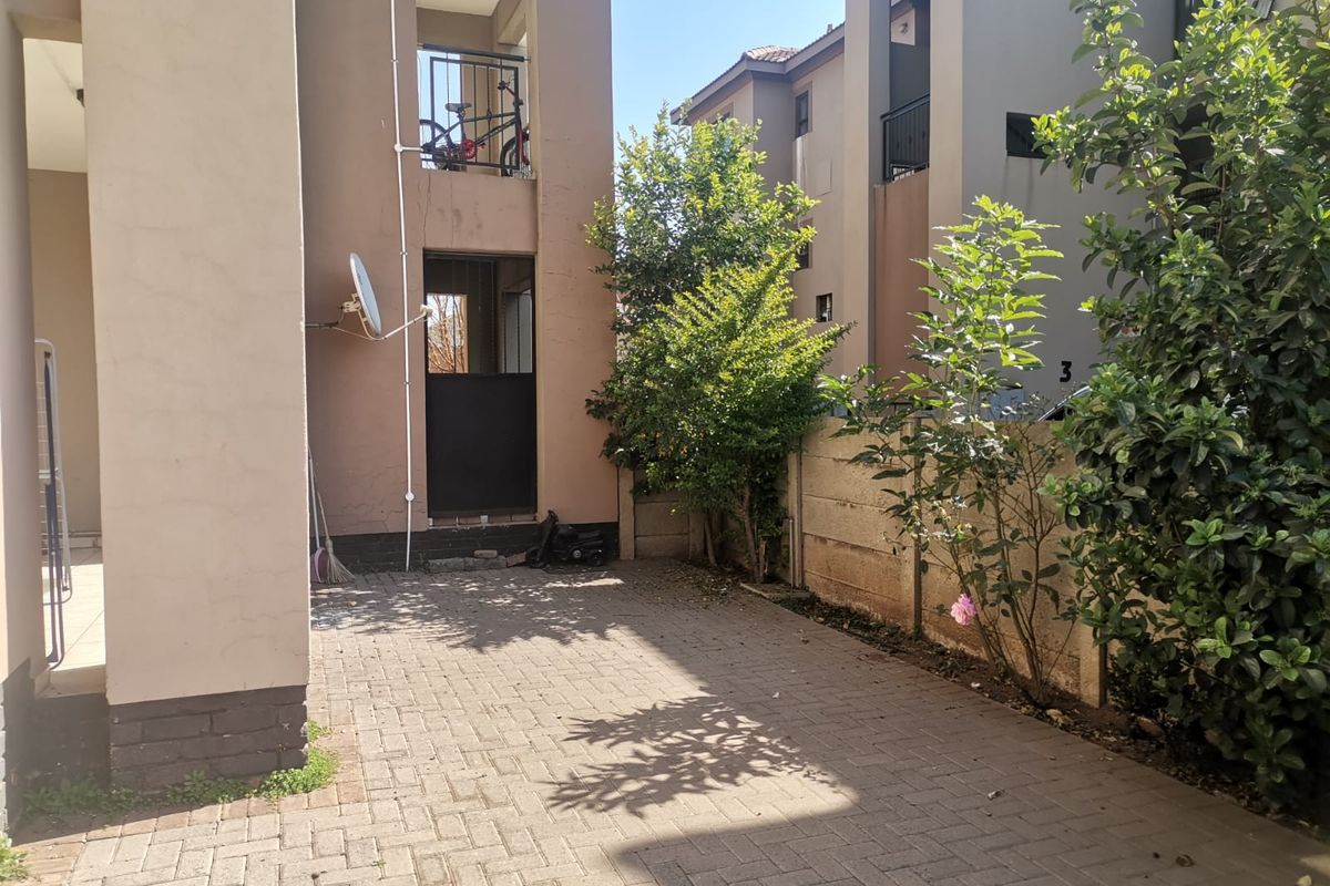 A paved rear courtyard area featuring a precast boundary wall and access to the apartment building's exterior structure.