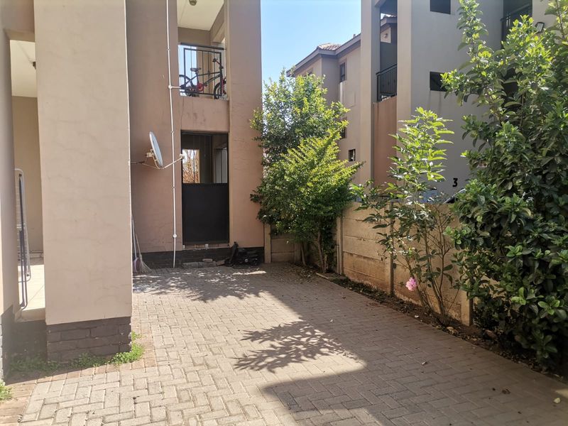 A paved rear courtyard area featuring a precast boundary wall and access to the apartment building's exterior structure.