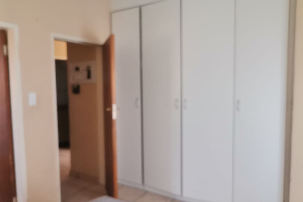 A bedroom featuring built-in cupboards and tiled flooring, providing a functional and neutral space.
