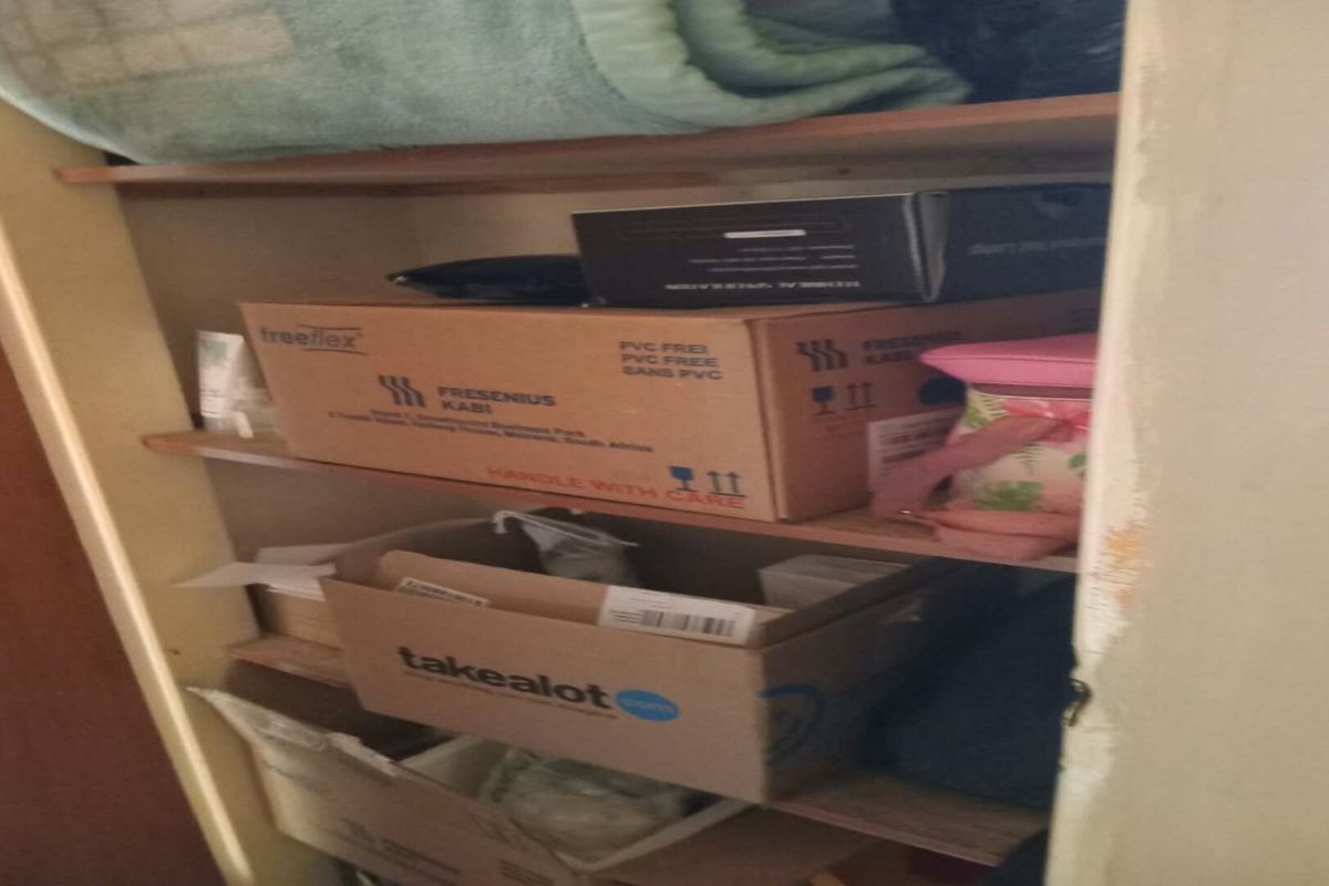 A storage cupboard featuring built-in wooden shelving, currently used for general household storage.