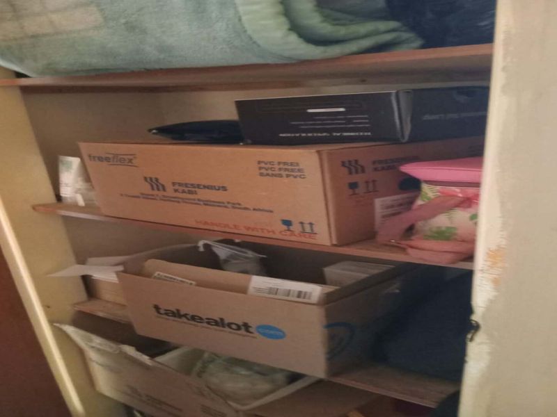 A storage cupboard featuring built-in wooden shelving, currently used for general household storage.