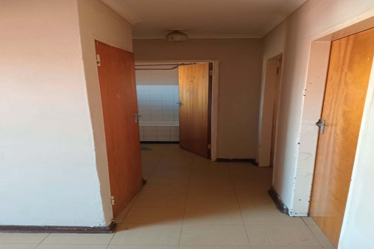 A vacant hallway featuring tiled flooring and wooden doors, providing access to adjacent rooms within the flat.