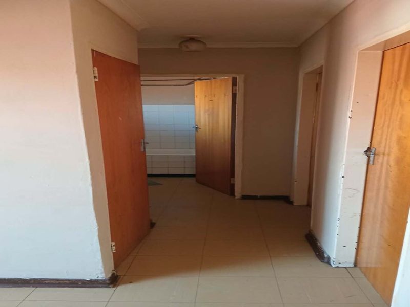 A vacant hallway featuring tiled flooring and wooden doors, providing access to adjacent rooms within the flat.