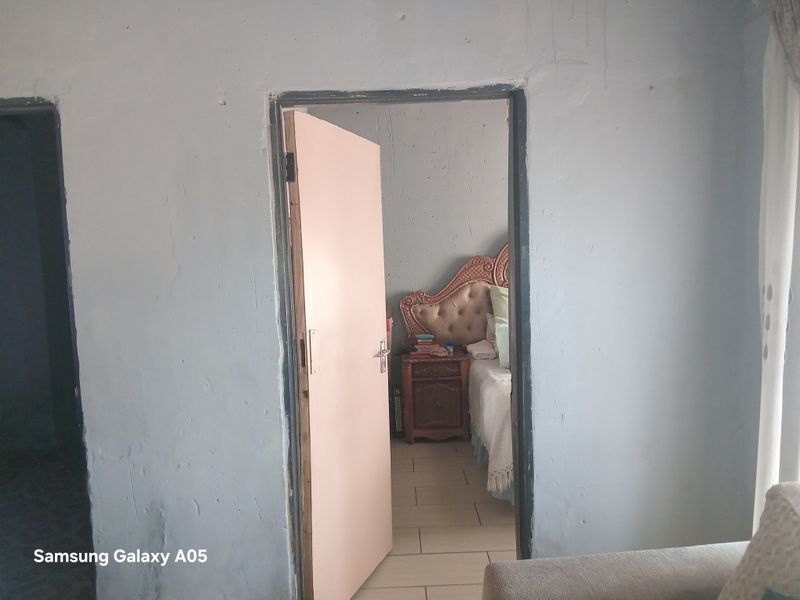 A view through a doorway into a bedroom from a hallway, featuring tiled flooring and painted wall surfaces.