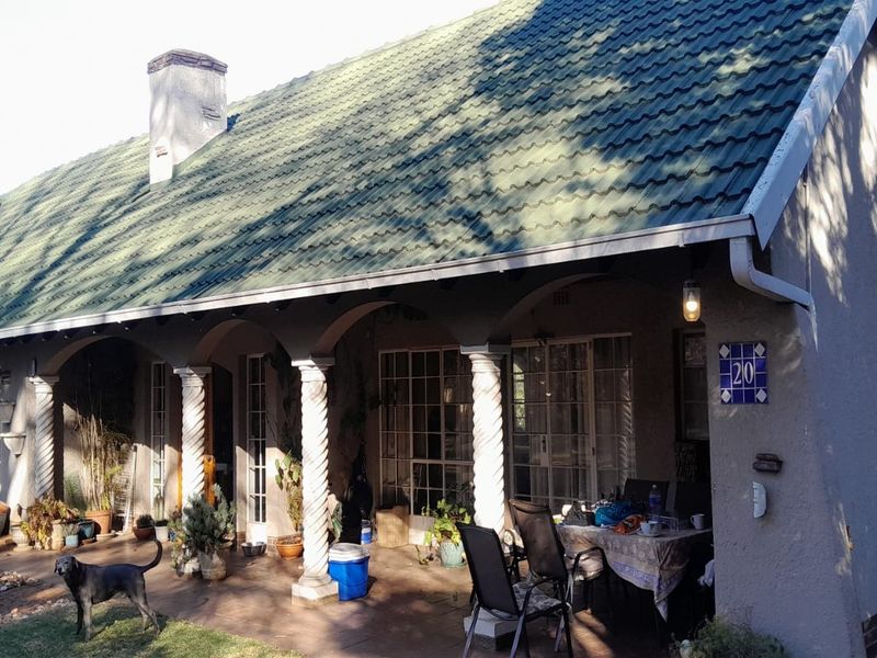 A covered patio area featuring decorative columns, tiled roofing, and paved flooring, providing a sheltered outdoor space for relaxation.