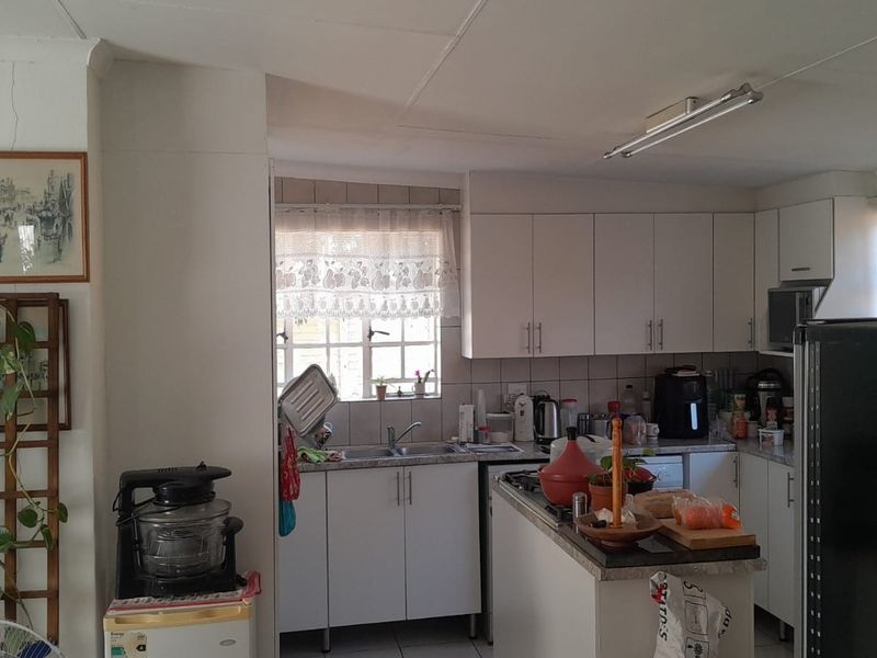 A functional kitchen featuring white cabinetry, laminate countertops, and a tiled backsplash, requiring some cosmetic updates to improve its overall aesthetic appeal.