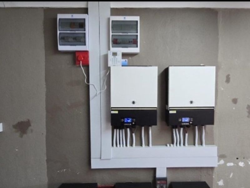 Utility area featuring dual solar inverters, electrical distribution boards, and built-in shelving units mounted on an unfinished wall.