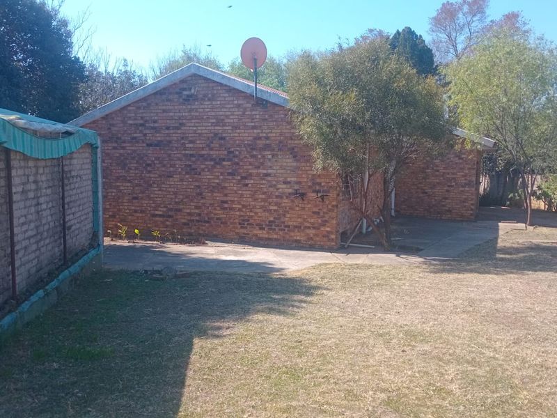 Rear view of a face brick house featuring a paved area and a large garden space.