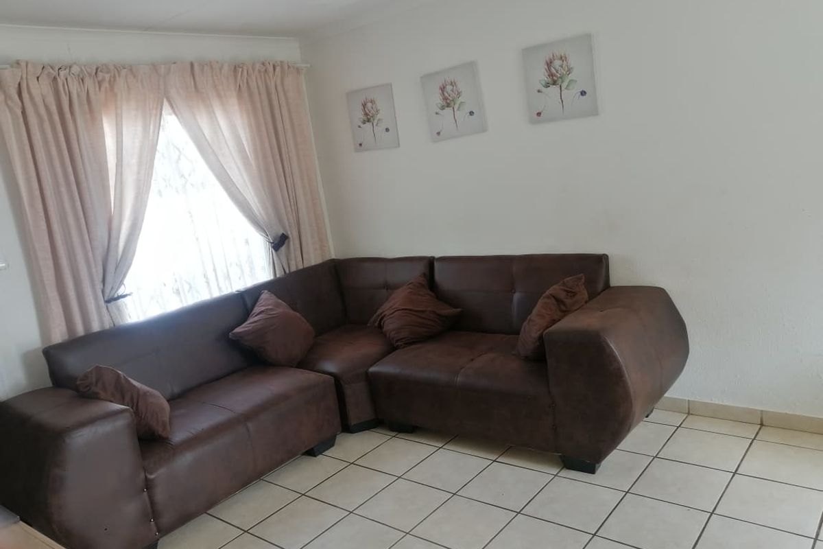 A living room area featuring neutral tiled flooring and window curtain rails, providing a functional and well-lit space.